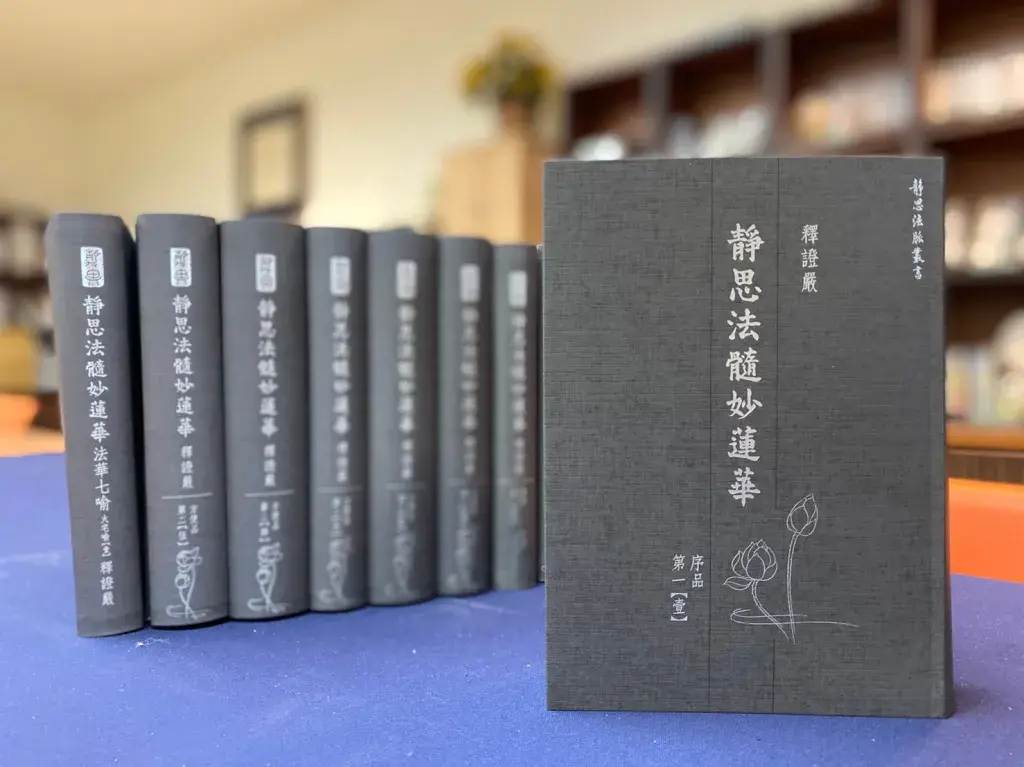 一排書籍，書名為《靜思法隨妙蓮華》，封面為深色設計，書籍整齊排列在桌上，背景模糊可見書架。
